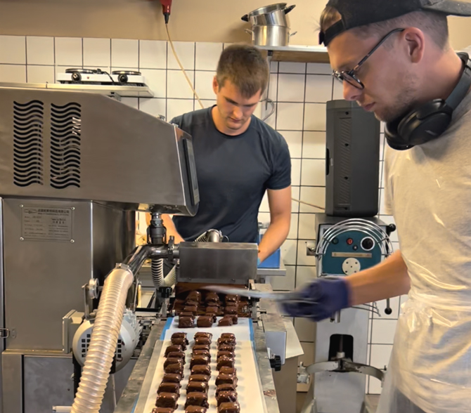Produktionsleder Martin Hansen overtrækker chokolade med en anden medarbejder